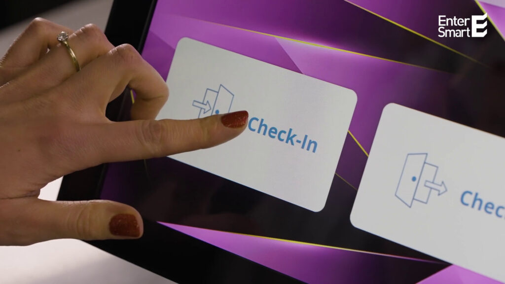 „Finger tippt auf Check-in-Button auf einem digitalen Empfangsterminal mit WELCOME-Benutzeroberfläche.“