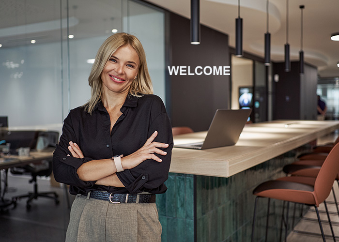 Managerin vor einem modernen Empfangsbereich, der mit WELCOME gemanagt wird.